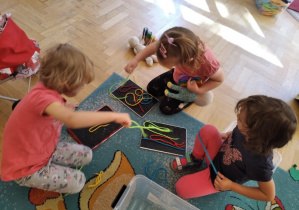 Dziewczynki bawią się na dywanie.